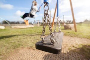 children on swingset with empty swing
