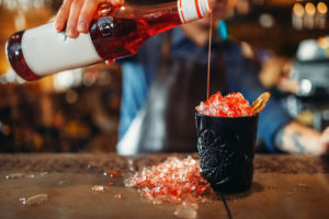 Barman pours beverage into the glass full of ice