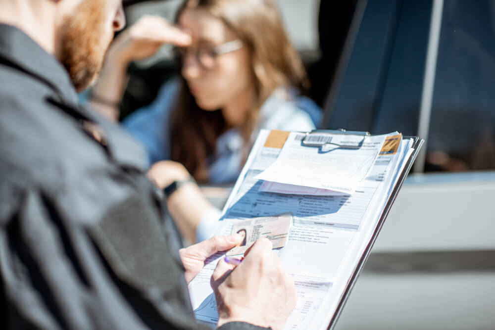 Policeman issuing a fine for violating the traffic rules to a young woman driver