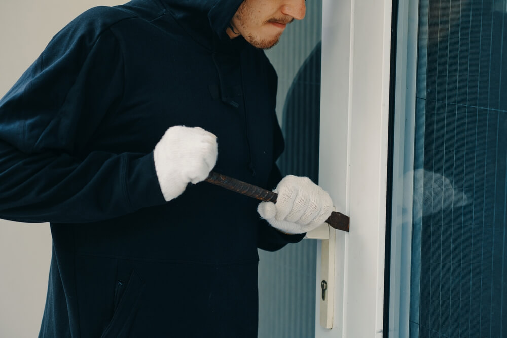 burglar with crowbar breaking door