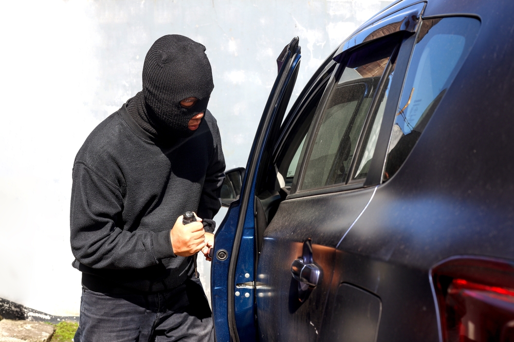 A criminal man with open the door and break into the car.