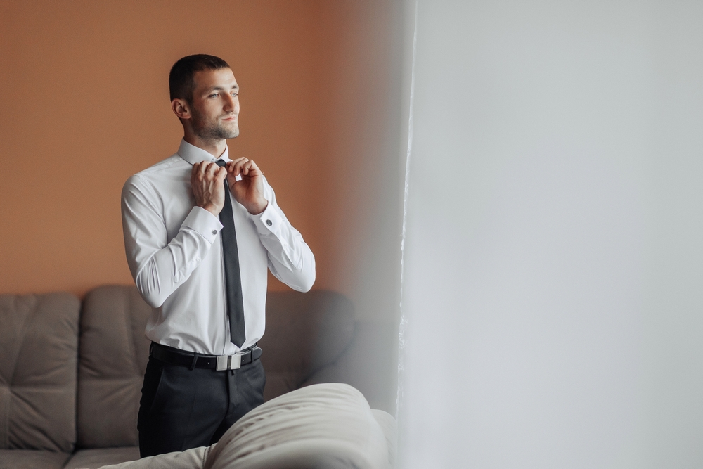 man putting tie on while getting ready